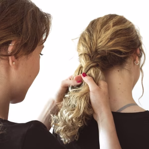 close-up-woman-making-her-sister-s-braid-against-white-background