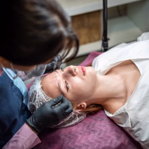 Permanent makeup cosmetologist master takes measurements for the new shape of the eyebrows of model. Microblading preparation. High quality photo