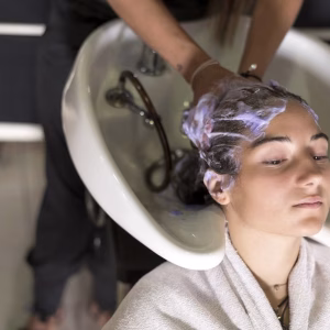 Top view of a hairdresser washing hair of a beautiful young woman in hair salon.