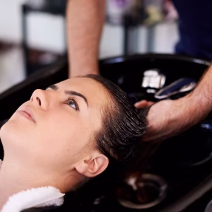 Woman, cleaning and shower in hair salon with hands, basin and process for hygiene, routine and wellness. People, service and washing for care with cosmetics for transformation, change and growth.